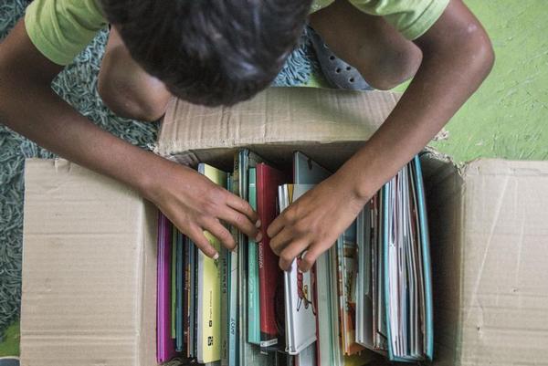 Un infant mira els llibres donats ©Cristobal Quesada (Terral Studio)